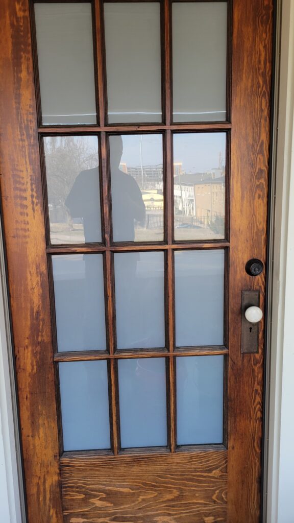 Rustic wooden entry door with frosted glass panes providing privacy and natural light.